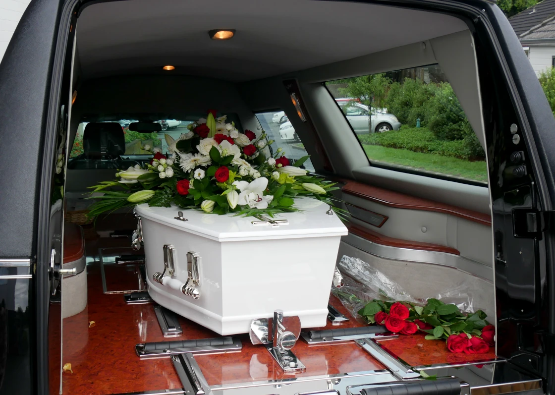 White coffin with flowers in hearse