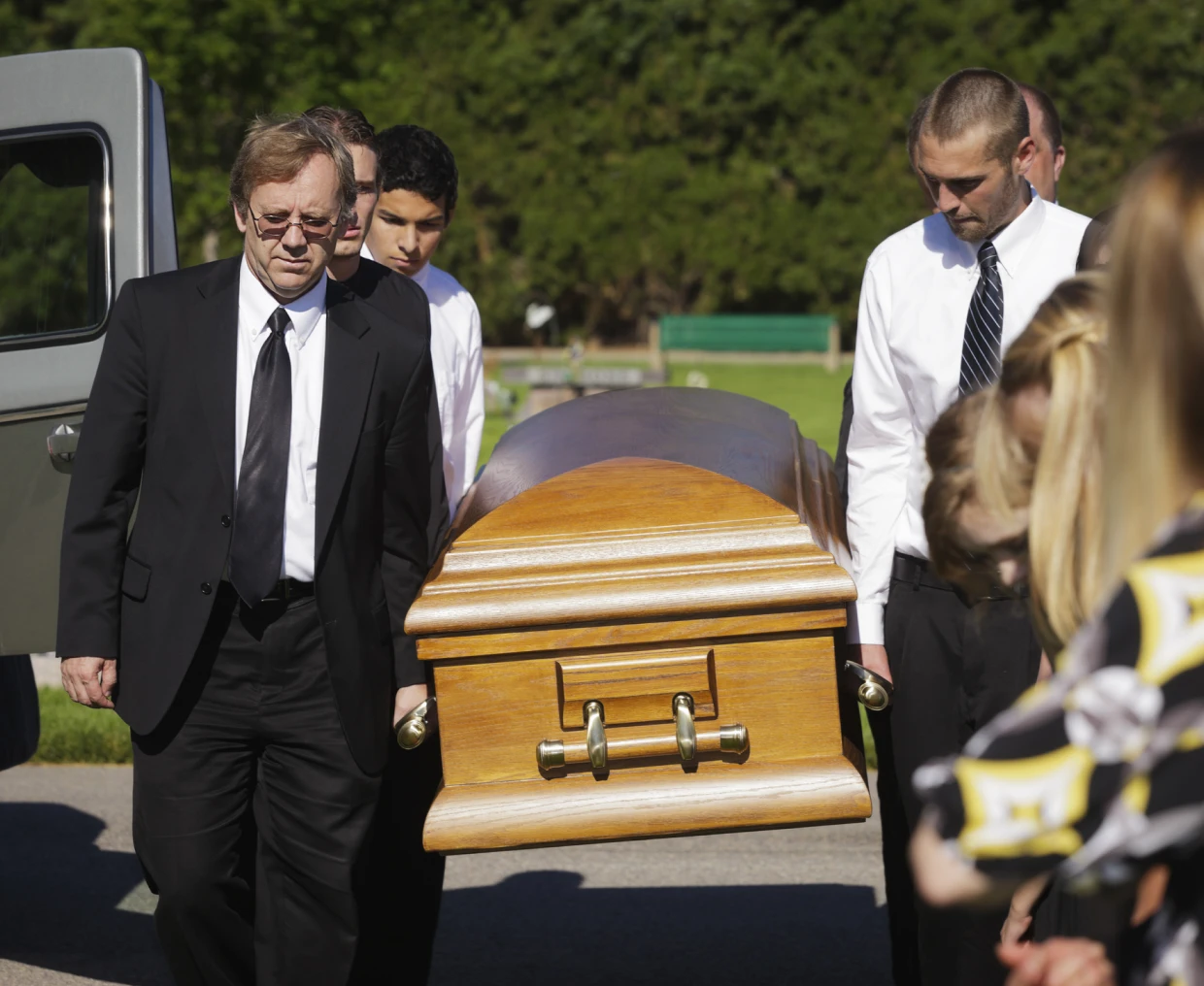 Men in suits carrying a coffin solemnly