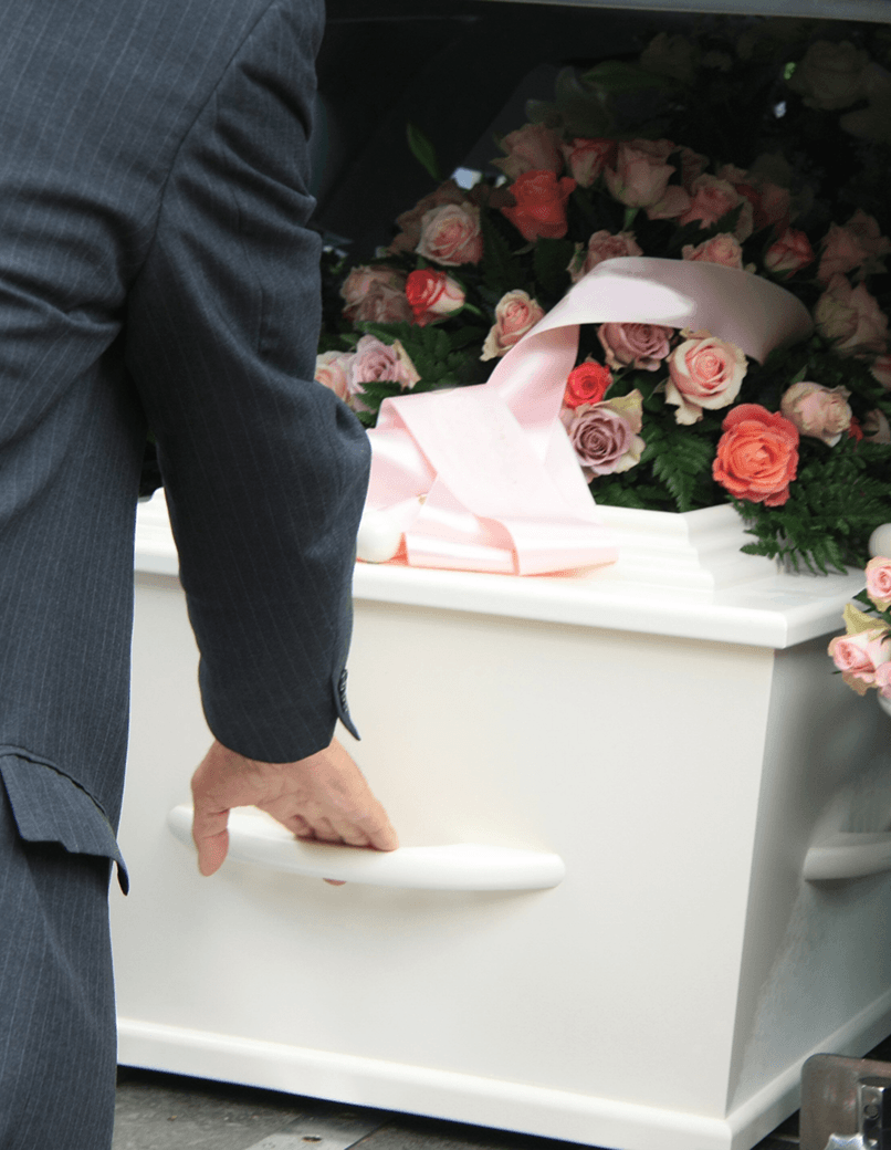 Pallbearer carrying white casket with flowers