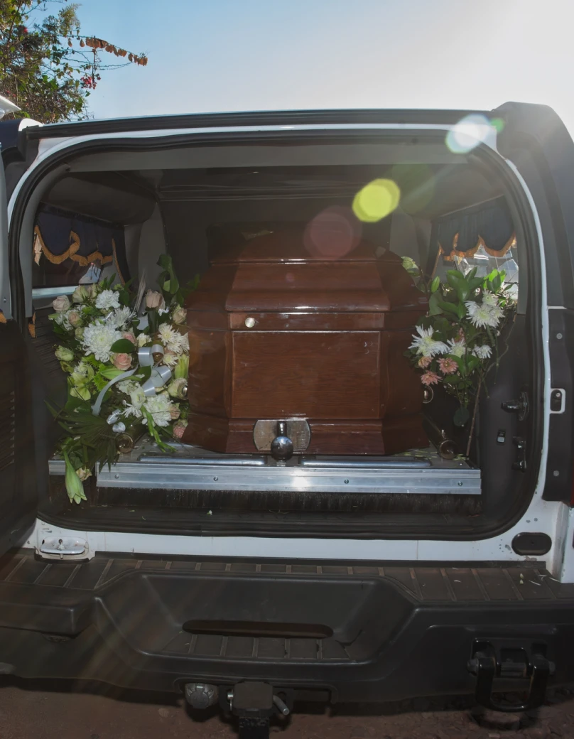 Casket inside hearse with floral arrangements